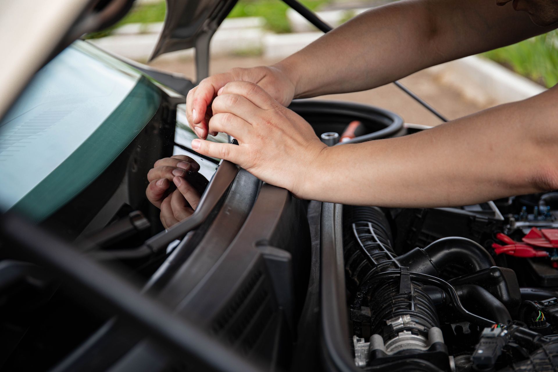 Close-up of a mechanic working on a car engine, focusing on hand adjustments.